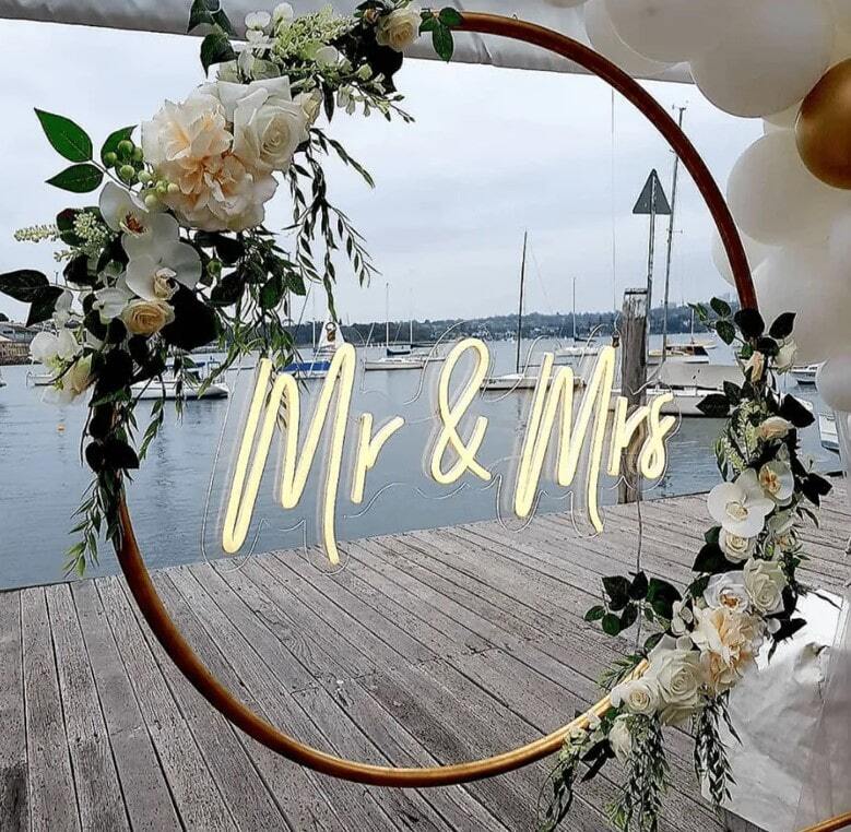 Тёплая неоновая надпись Mr & Mrs на круглом оформлении с цветами