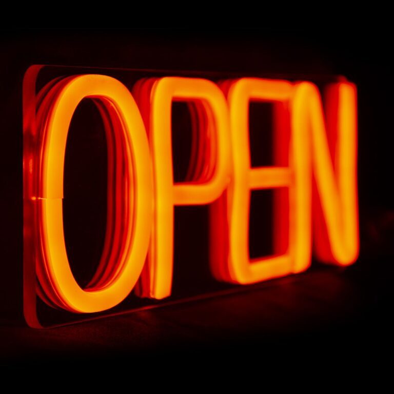 Крупный план оранжевой неоновой надписи OPEN и прозрачного основания